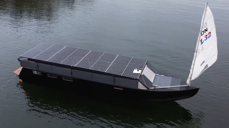 A yacht with solar panels and a sail sits in water