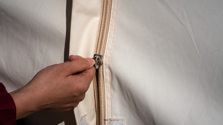 Person holding zipper of camping tent while inside it
