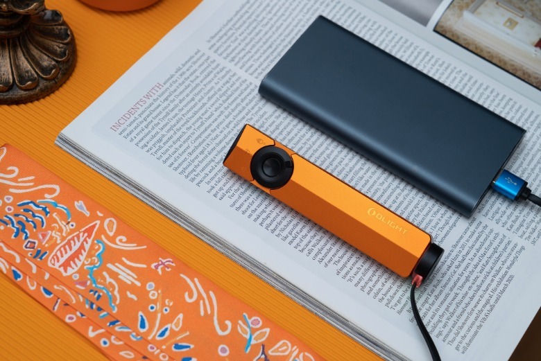 ArkPro Orange being charged by power bank on a book