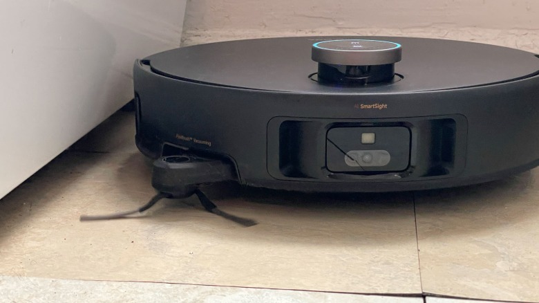 Robot vacuum with brush spinning in bathroom.