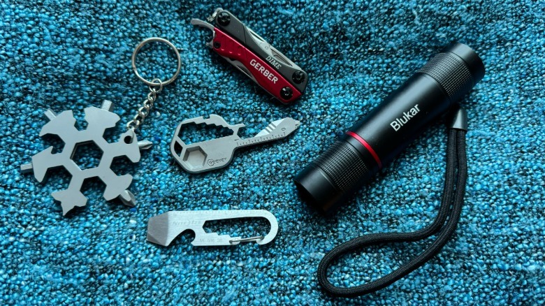 Five different keychain tools are laid out