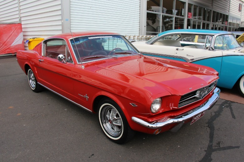Red 1965 Ford Mustang Fastback parked at a car show