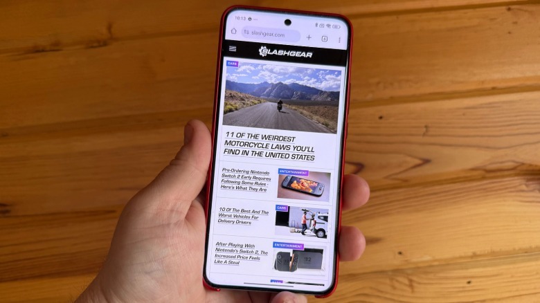 Smartphone held by hand in front of wood wall.