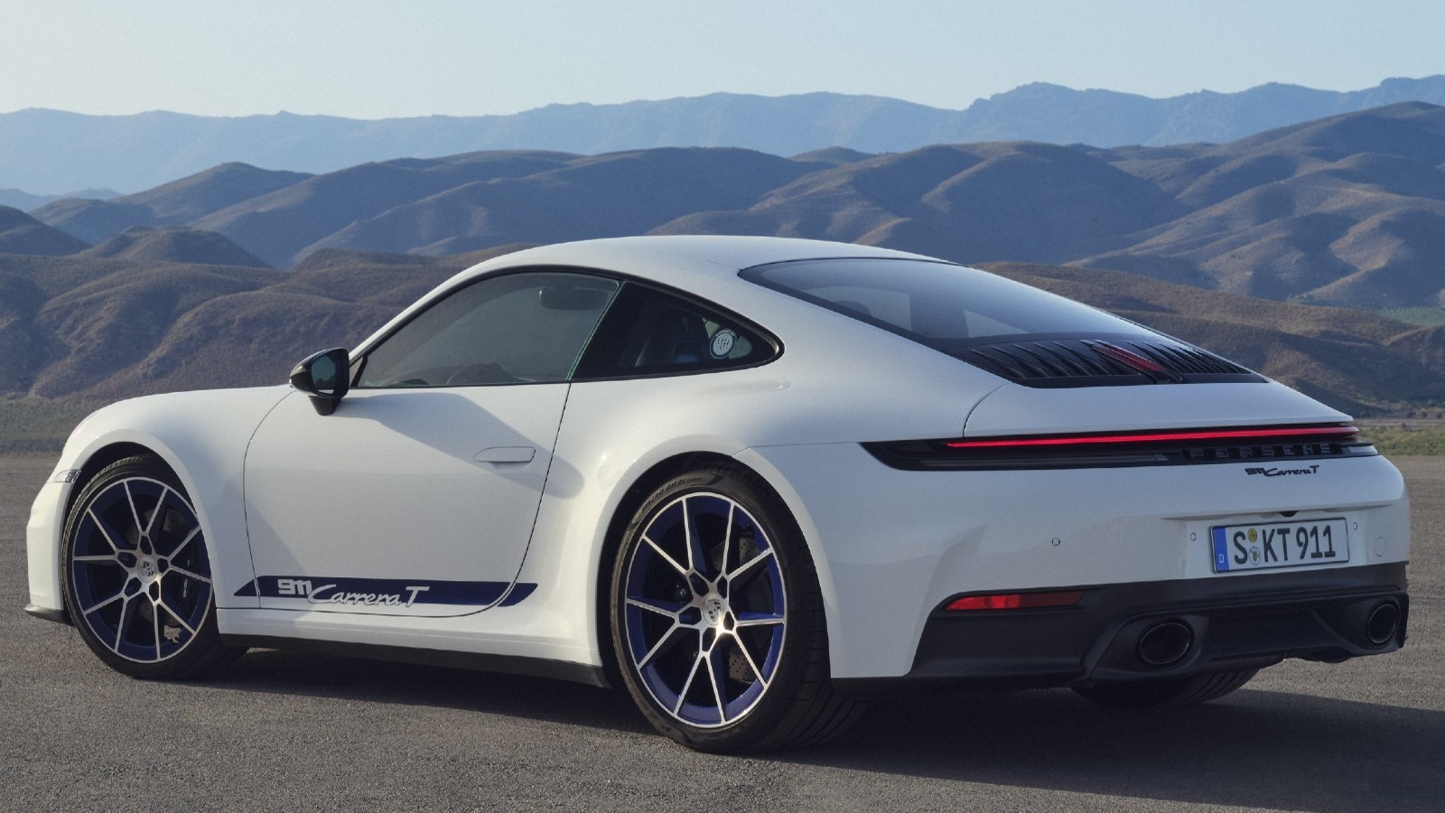 White Porsche 911 Carrera T Coupe on road in front of mountains