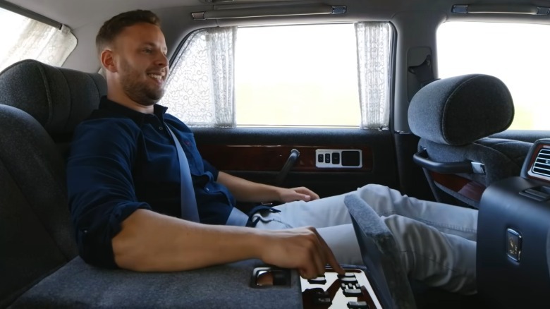 Man in back seat of Toyota Century with legs extended through front passenger seat