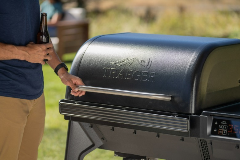Person holding the lid handle of a Traeger Woodridge grill.